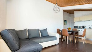 En moderne stue med sofa, spisebord og stole. En geometrisk pendel hænger fra loftet.
