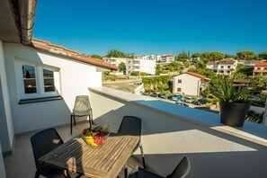 Ein Balkon mit Tisch und Stühlen, einem Blumentopf und freiem Blick auf die umliegende Gegend.