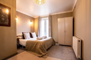 A bedroom with a bed, bedside tables, a wardrobe, and a radiator.