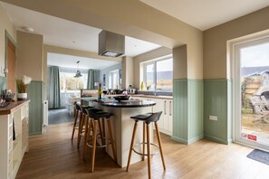A modern kitchen with a central island, bar stools, and a view of the backyard.