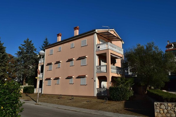 A multi-story building with a flat roof, balconies, and a clear sky. - Apartment Valter with Balcony (Malinska)