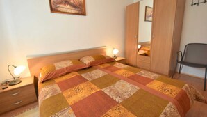 Quarto com cama, mesas de cabeceira, guarda-roupa, cadeira e um quadro na parede.