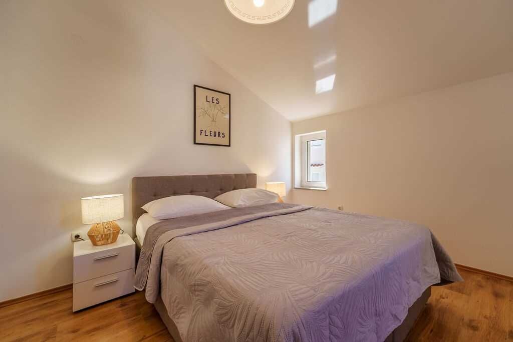 Een slaapkamer met een bed, nachtkastje en wanddecoratie.