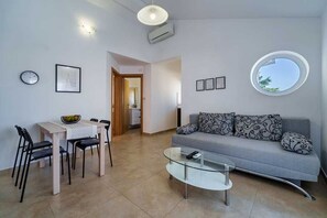 Ein modernes Wohnzimmer mit einer Couch, einem Glastisch und einem Essbereich mit Stühlen und einem Tisch.