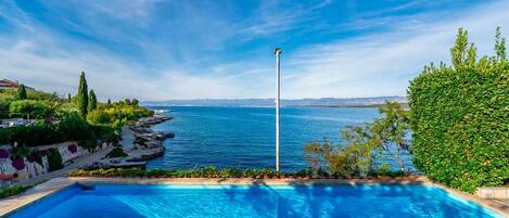 A swimming pool with a view of the sea and a clear sky.