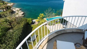 Un balcon avec vue sur une piscine et la mer.