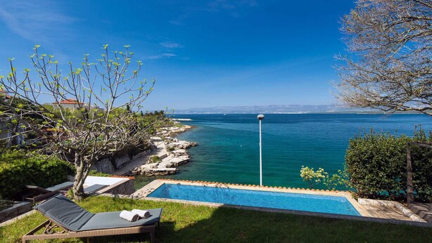 Une piscine avec vue sur la mer, une plage et un ciel dégagé.