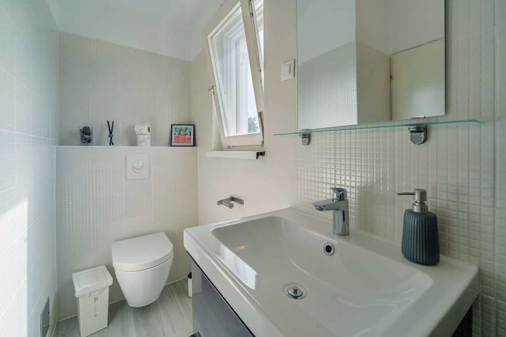 A modern bathroom with a large sink, toilet, and a window.