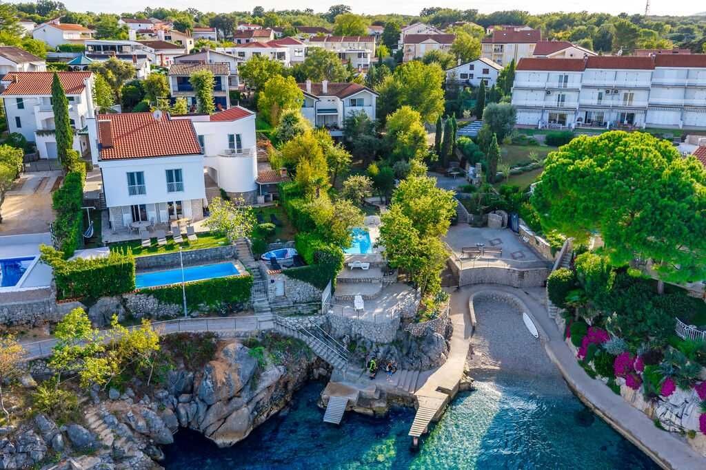 A residential area with houses, a swimming pool, and a rocky waterfront.
