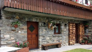 Un edificio de piedra con puerta de madera, un banco y plantas en macetas.