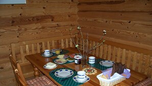 Un tavolo da pranzo in legno apparecchiato con piatti, ciotole e un vaso con dei rami.