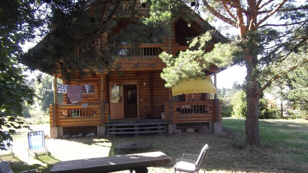 Una baita di legno con veranda, tavolo da picnic e sedie.