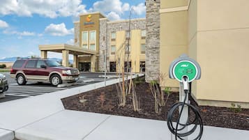 Un hôtel doté d’un parking, d’une borne de recharge et d’un bâtiment à la façade en pierre.