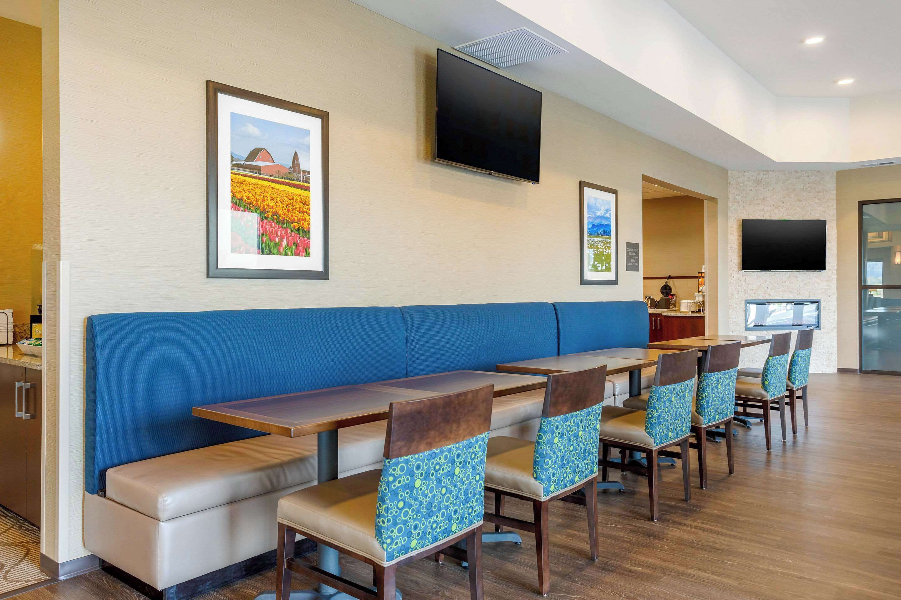 A restaurant with a long counter, blue cushioned seating, and a flat-screen TV mounted on the wall.