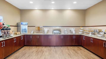 A hotel kitchen with a long counter, various appliances, and storage cabinets.