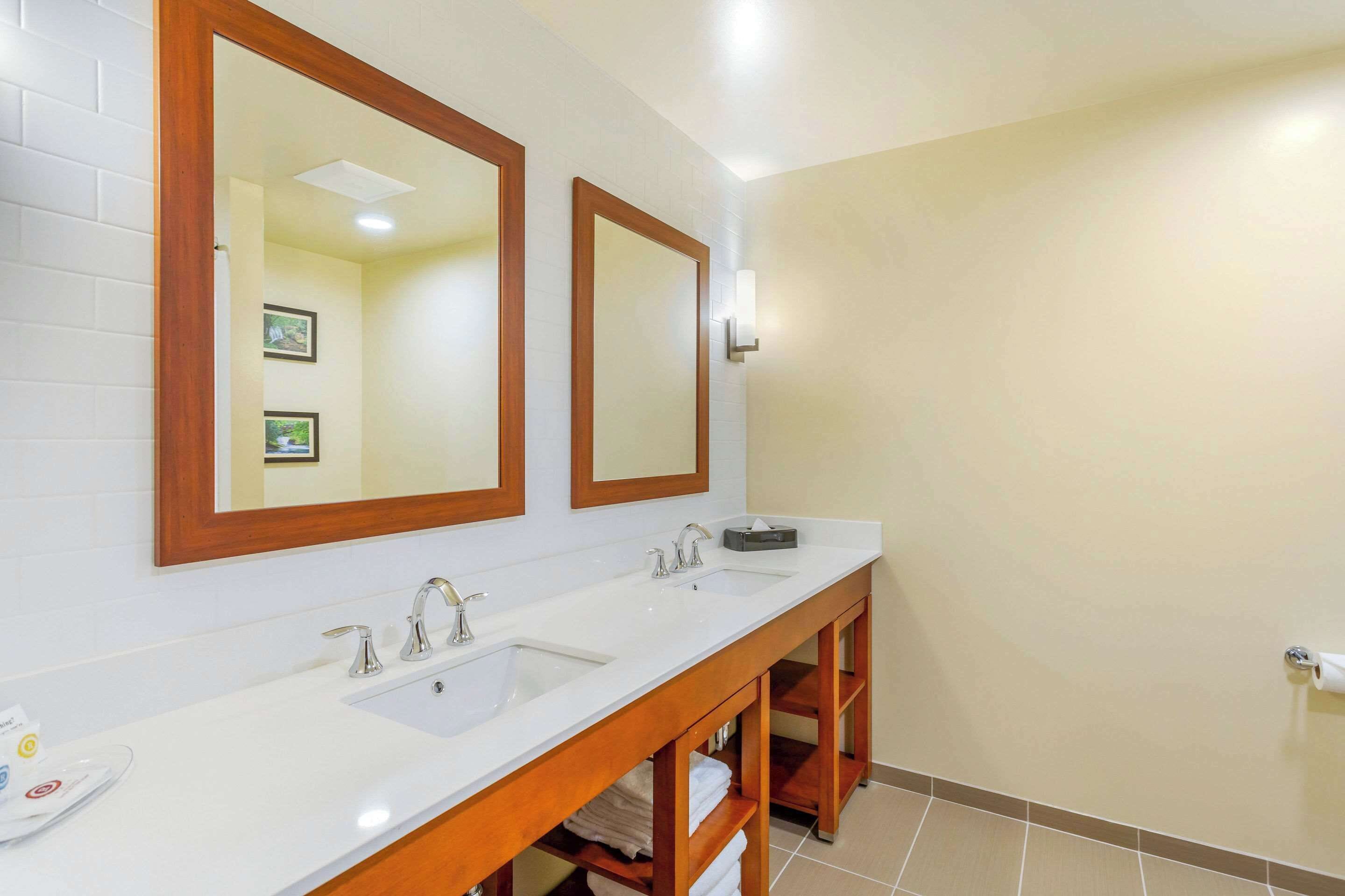 Une salle de bain avec deux lavabos, un meuble-lavabo en bois et de grands miroirs.