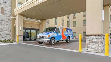 Een bestelwagen geparkeerd voor een hotelingang met een stenen gevel en een overdekte doorgang.