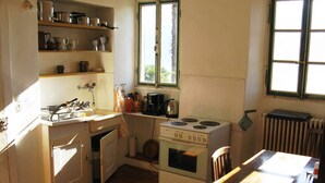 Une cuisine de taille réduite, équipée d’une cuisinière, d’un évier et d’étagères au-dessus du plan de travail.