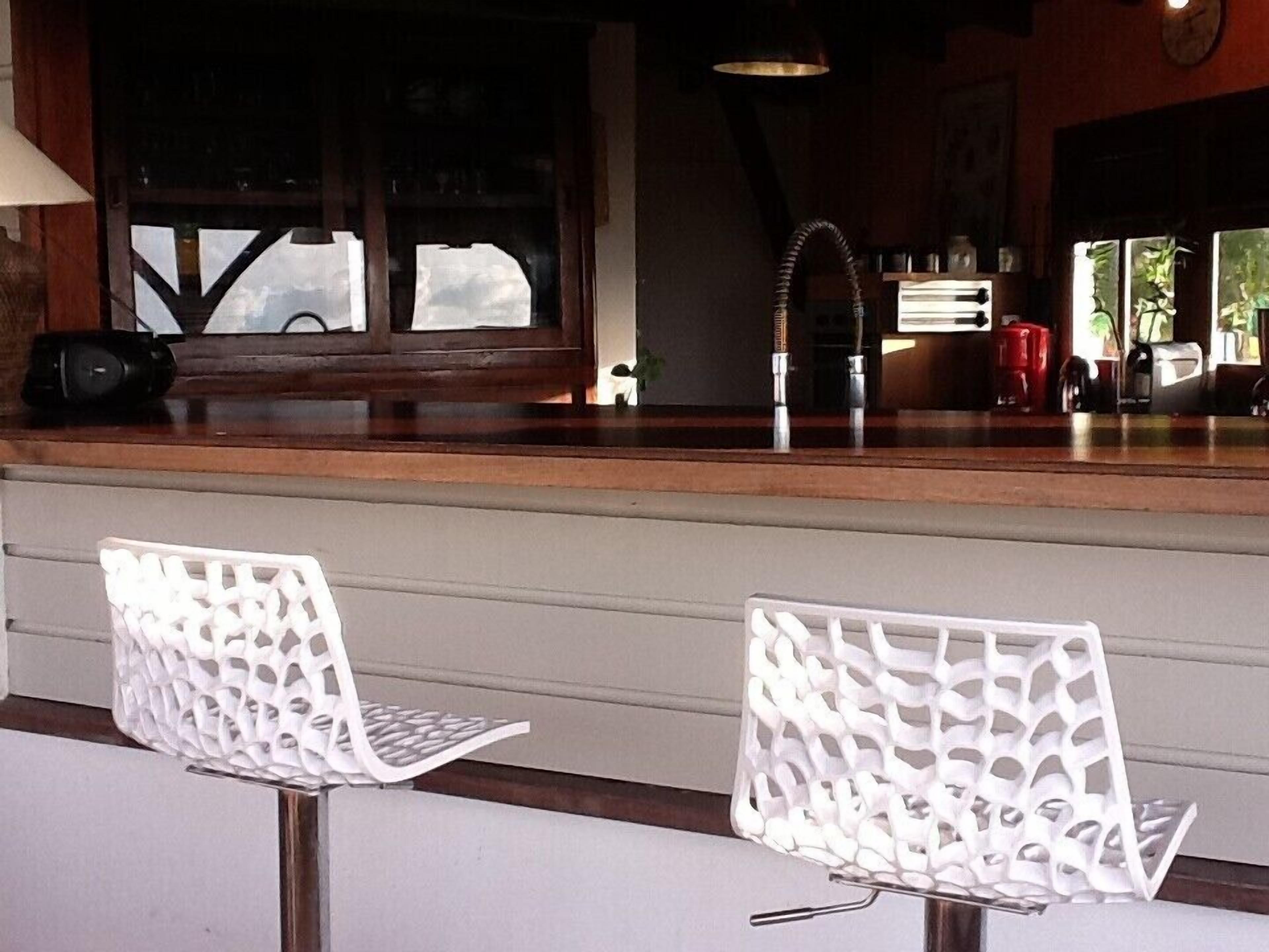 A bar area with two white chairs, a wooden counter, and a window with a view.