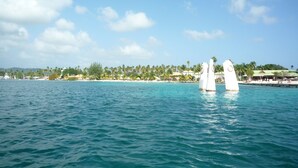 A coastal scene with a clear sky, calm sea, and a row of white structures in the water. - Studio with private jacuzzi (Sainte-Anne)
