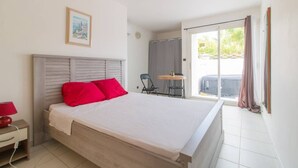 A bedroom with a bed, a nightstand, a chair, and a small table. - Studio with private jacuzzi (Sainte-Anne)