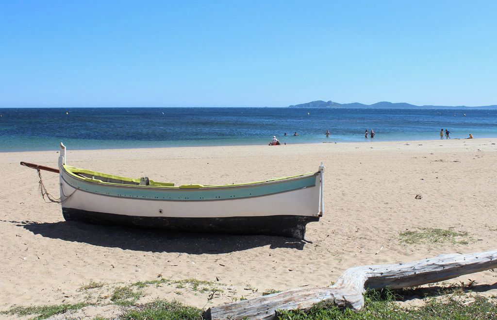 Una barca su una spiaggia sabbiosa con vista libera sul mare e montagne in lontananza.