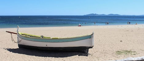 Una barca su una spiaggia sabbiosa con vista libera sul mare e montagne in lontananza.
