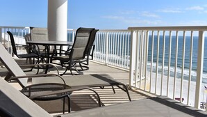 Un balcon avec une table et des chaises, donnant sur une plage.