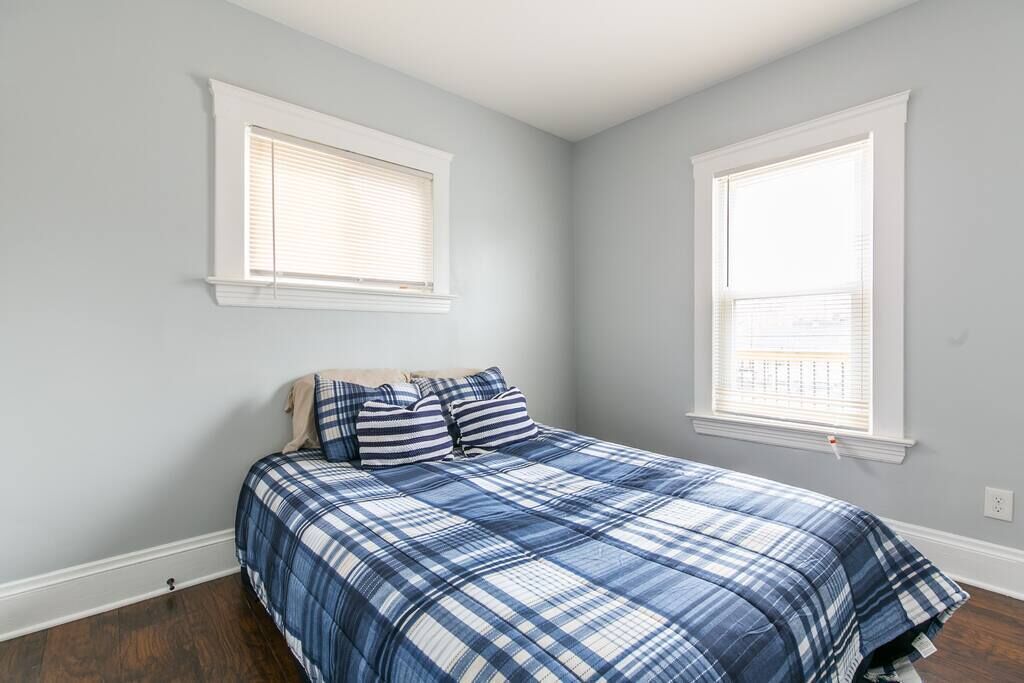 Une chambre à coucher avec un lit, deux fenêtres et un mur blanc.