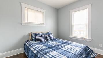Une chambre à coucher avec un lit, deux fenêtres et un mur blanc.