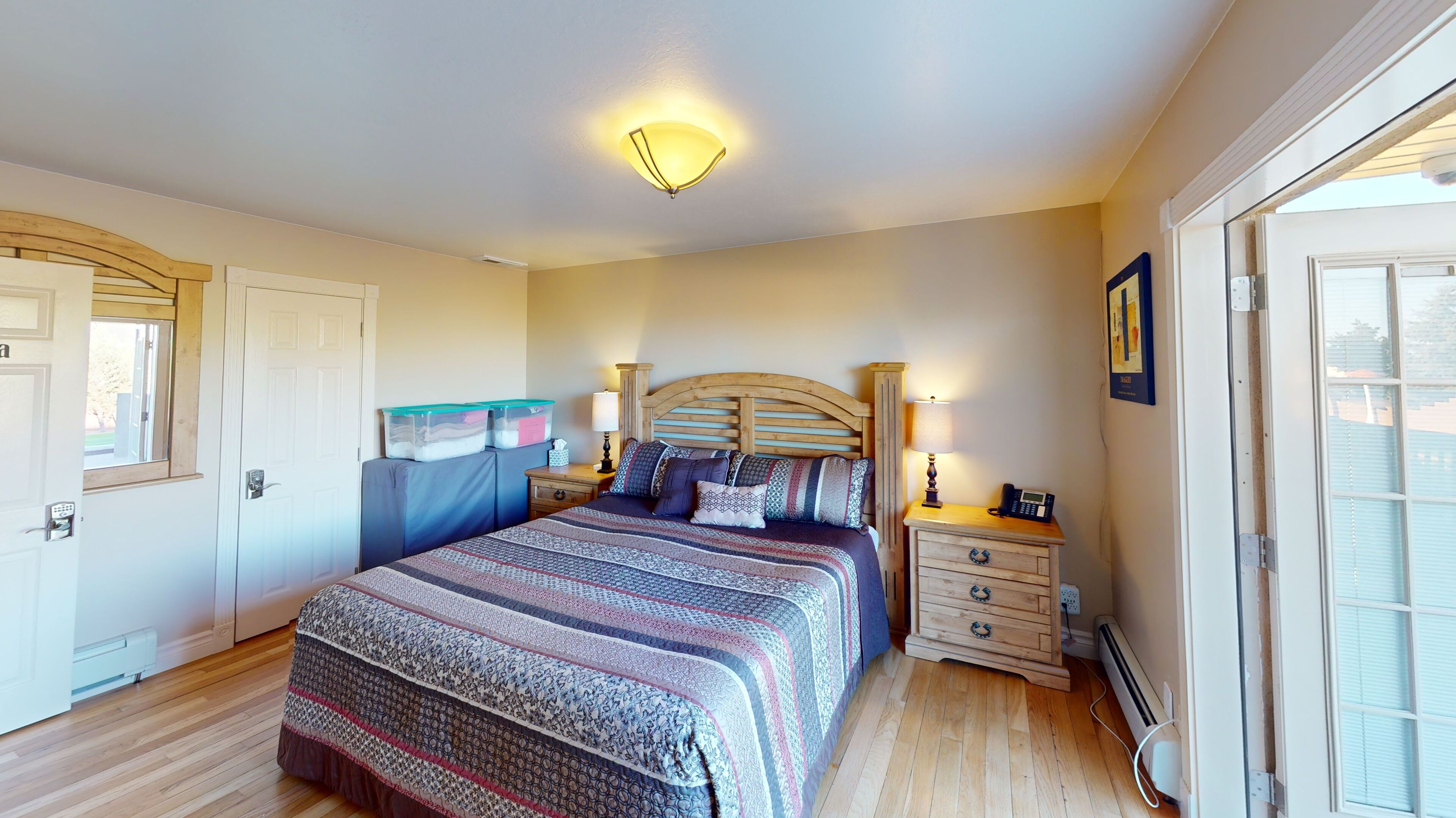 Un dormitorio con cama, mesitas de noche, lámpara, calefactor y contenedores de almacenamiento en la pared.