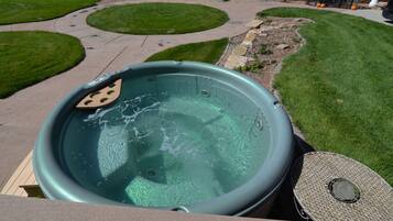Un jacuzzi en un área exterior ajardinada con un sendero de piedra y zonas cubiertas de césped.