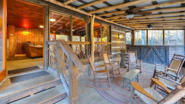 Interior de madera con suelo de piedra, sillas de madera, una pequeña mesa y una escalera que lleva a una habitación con sofá de cuero.