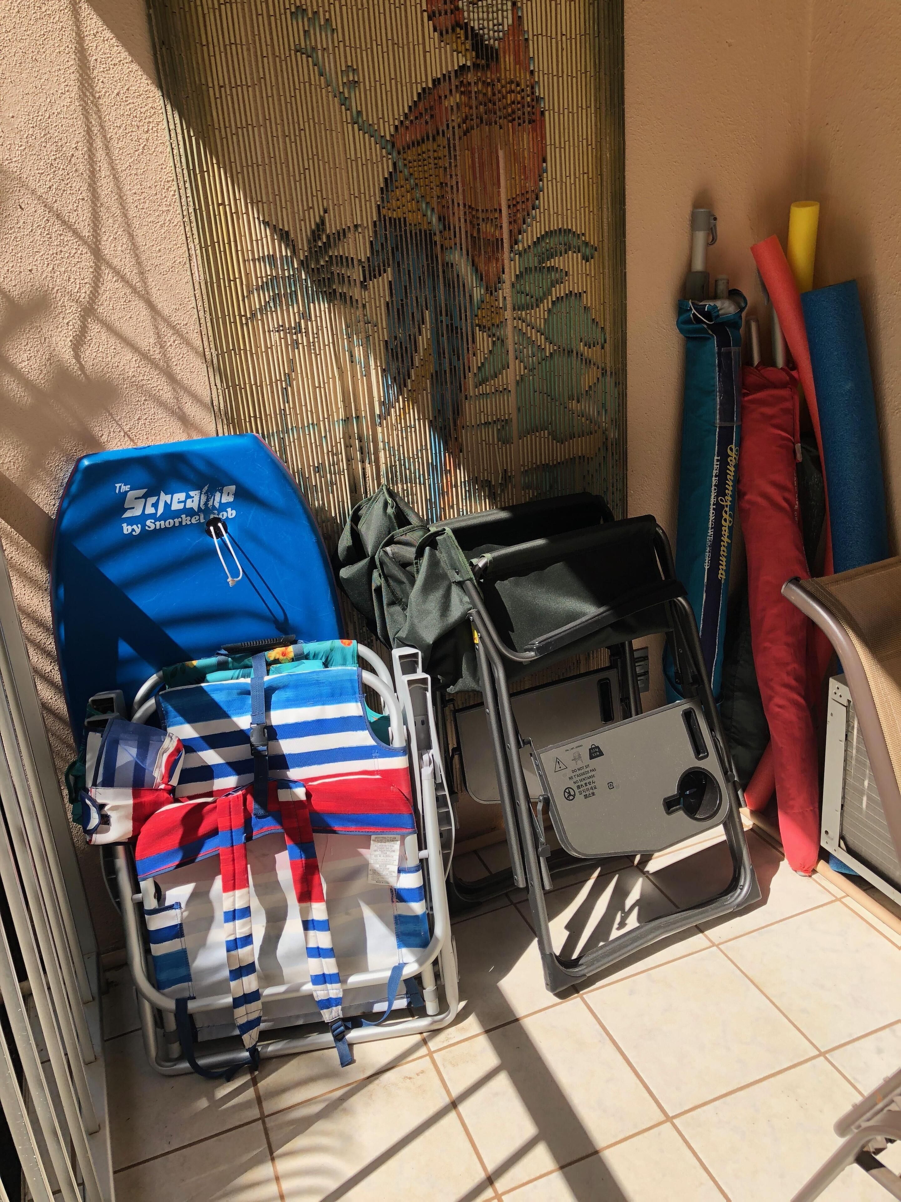 A room with a tiled floor, a blue and red striped bag, a blue backpack, and a black chair with a tray.