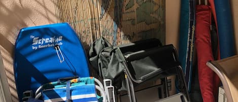 A room with a tiled floor, a blue and red striped bag, a blue backpack, and a black chair with a tray.