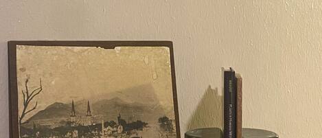 A framed historical photograph, a book, and two clear glass vases on a woven shelf.