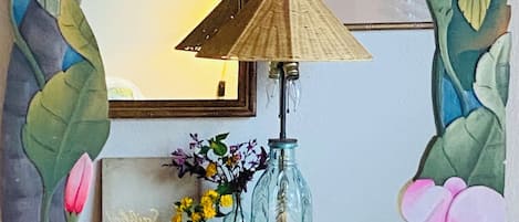 A mirror with a decorative frame, a lamp, and a vase with flowers.