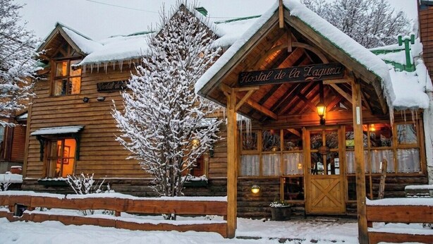 A wooden lodge with a snow-covered roof and a sign reading "Hostal de la Laguna". - Hostal de la Laguna (Ushuaia)