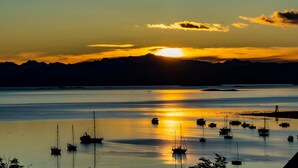 A calm harbor with boats at sunset, mountains in the background, and a clear sky. - Hostal de la Laguna (Ushuaia)