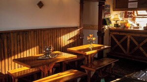 A cozy restaurant interior with wooden benches and tables, warm lighting, and a wooden wall. - Hostal de la Laguna (Ushuaia)