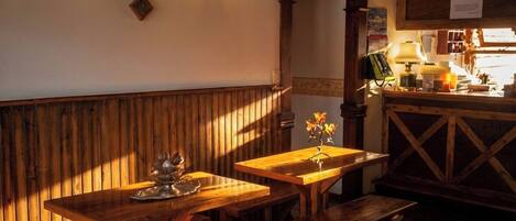 Interior acogedor de restaurante con bancos y mesas de madera, iluminación cálida y una pared de madera.
