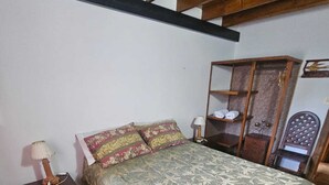 A bedroom with a bed, a nightstand, a wooden wardrobe, and a chair. - Hostal de la Laguna (Ushuaia)