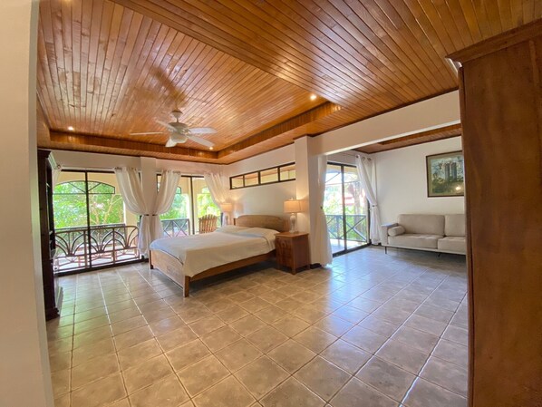 Relax in this serene bedroom with a large bed, ceiling fan, and sliding glass door leading to a balcony.