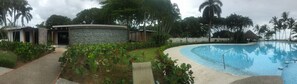 Relax by the well-maintained pool surrounded by lush greenery and palm trees.
