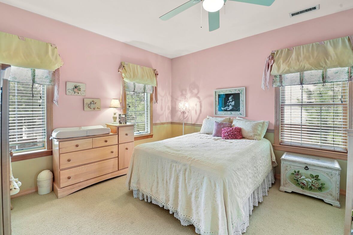 Un dormitorio con cama, cómoda, tocador y una ventana con cortinas.