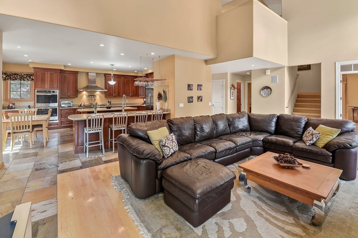 A spacious living area with a leather sectional sofa, a wooden coffee table, and a dining area with a bar.