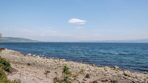 Une côte rocheuse offrant une vue sur la mer et les collines lointaines.