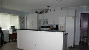 Una cocina con armarios blancos, una isla central, un microondas y un refrigerador.