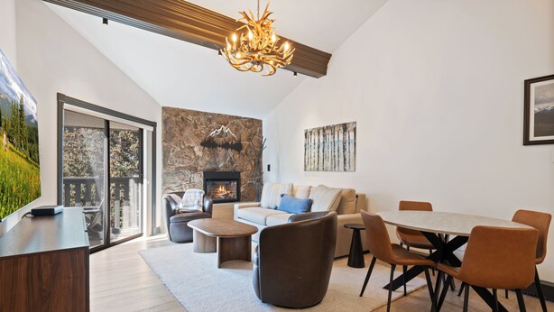 Uma sala de estar moderna com lareira, área de jantar e uma grande janela com vista para um jardim.