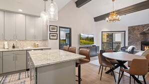 Uma cozinha moderna com bancadas de granito, eletrodomésticos de aço inoxidável e uma área de jantar com mesa redonda e cadeiras de couro.